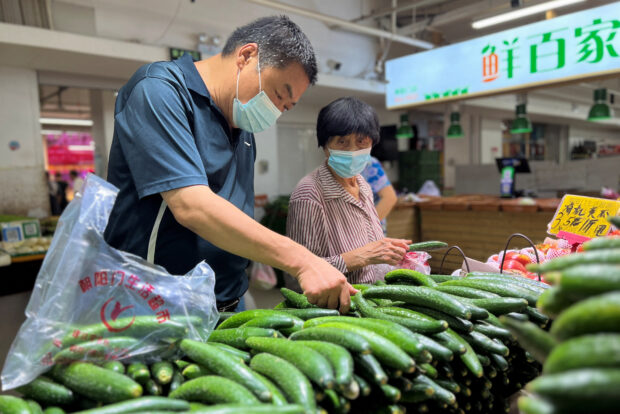 Customers shop vegetables at a wet market in Beijing