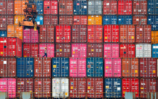A worker walks on stacks of containers at Tanjung Priok port in Jakarta