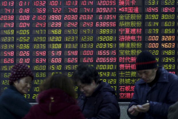 People stand in front of an electronic stock quotation board in Shanghai