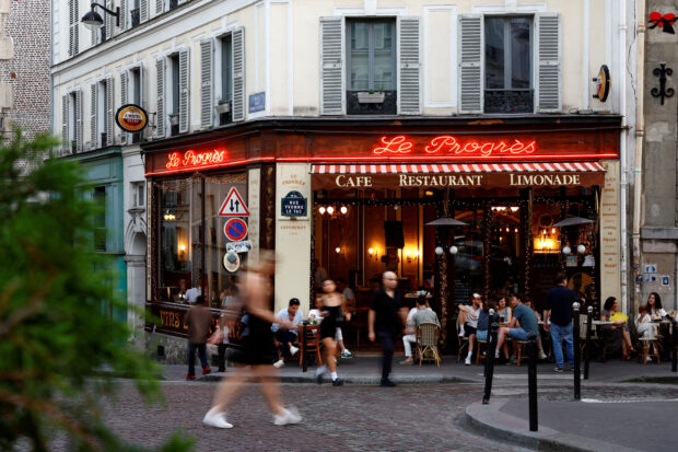 People walk past a restaurant at the Butte Montrmartre in Paris