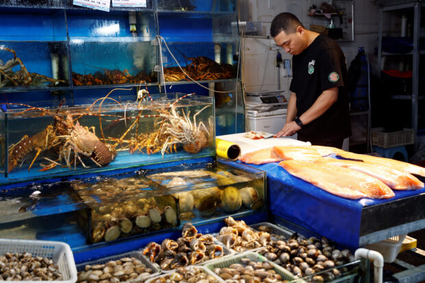 A vendor processes surf clams at seafood market in Beijing 