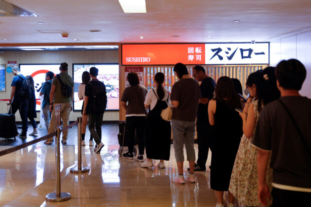 Customers queue in front of a sushi restaurant in Hong Kong