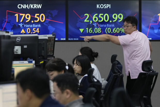 A currency trader gestures in front of screens showing the Koeran Composite Stock Price Index