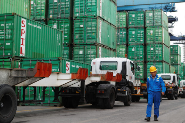 A worker walks past stacks of containers at Tanjung Priok port in Jakarta