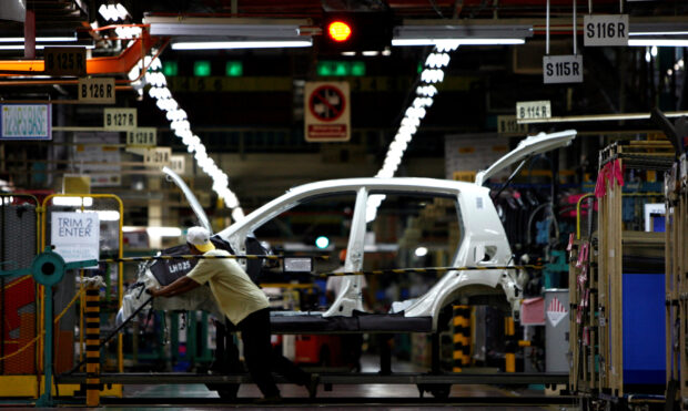 A worker pushes a frame of Malaysian made Perodua car