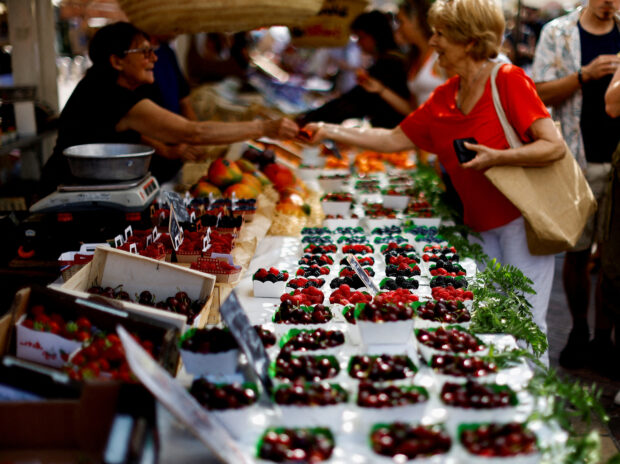 Shoppers buy fruits at a local market in Nice