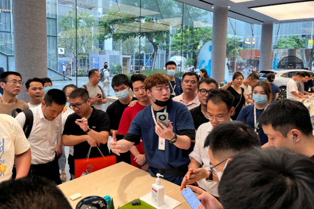 A staff member introduces new Huawei Mate 60 smartphone to customers at a store in Shenzhen