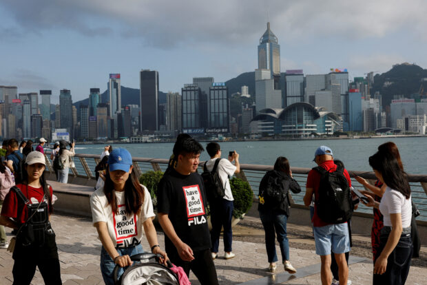 Chinese tourists walk in front of the skyline of buildings
