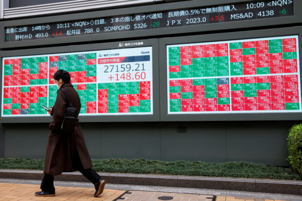 Man walks past an electronic board showing Japan's Nikkei average in Tokyo