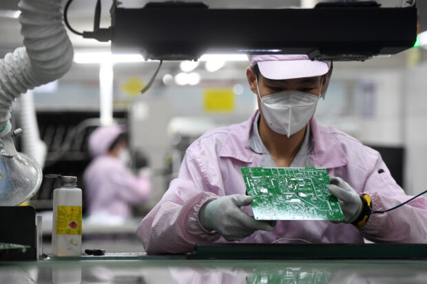 An employee inspects a circuit board at Gree factory in Wuhan