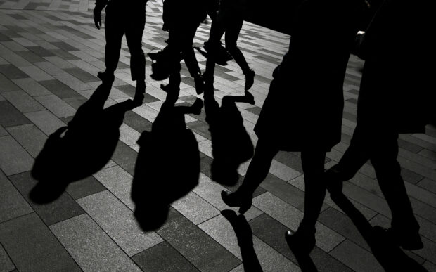 Workers cast shadows as they stroll in a Sydney office district