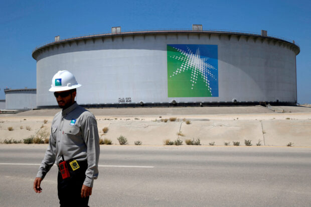 An Aramco employee walks near an oil tank at Aramco oil refinery and terminal in Saudi Arabia
