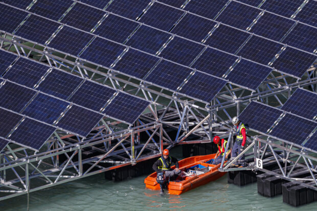 Workers assemble floating barges with solar panels in Switzerland