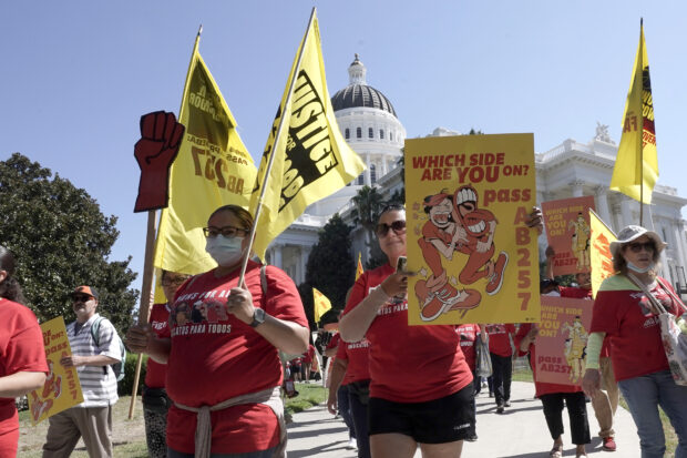 Fast food workers and supporters march past the California state capitol in Sacramento