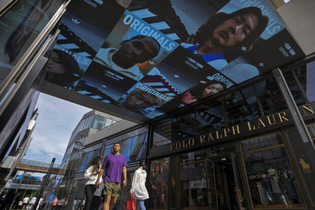 People walk through a screen ad at a shopping mall in Beijing