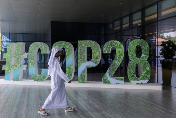 A person walks past a #COP28 sign in Abu Dhabi