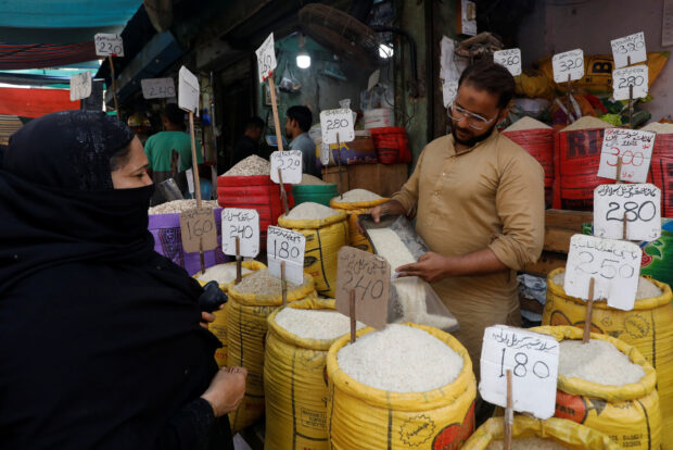 Shopkeeper fills a bag of rice for a customer in a market in Karachi