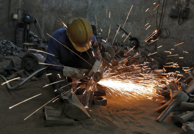 A worker welding metal shaft at a manufacturing unit in Ahmedabad