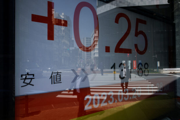 A reflection of passersby is reflected on an electronic board showing Nikkei average in Tokyo