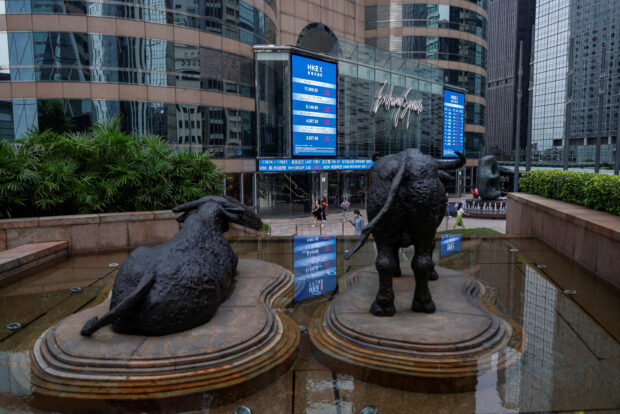 Bull statues in front of screens showing the Hang Seng stock index in Hong Kong