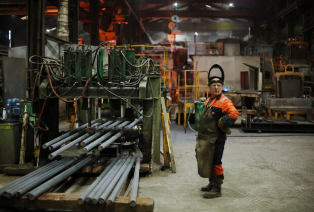 A worker stands next to a machine at the United Cast Bar Group's foundry in Britain