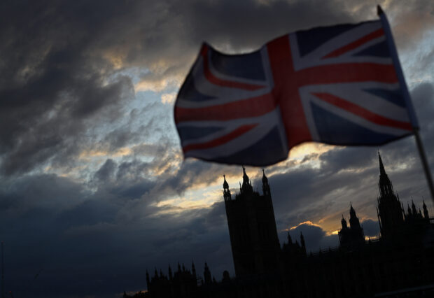 A Union Jack flag flutters in front of the Houses of Parliament