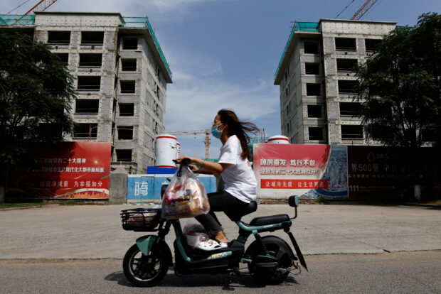 Person rides a scooter past a construction site of residential buildings of Chinese developer Country Garden