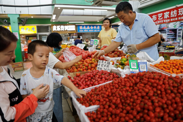 Customers buying tomatoes at a stall in a morning market in Beijing