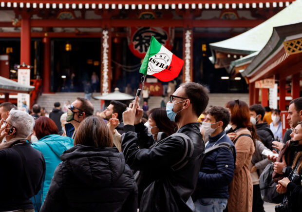 A tour guide leads a tourist group from Italy at Asakusa district