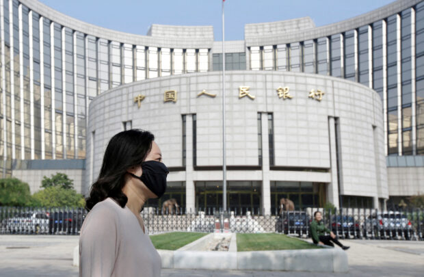Woman walks past the headquarters of the People's Bank of China