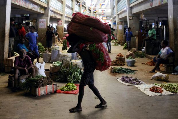 A worker carries a sack of vegetables at the wholesale market in Sri Lanka
