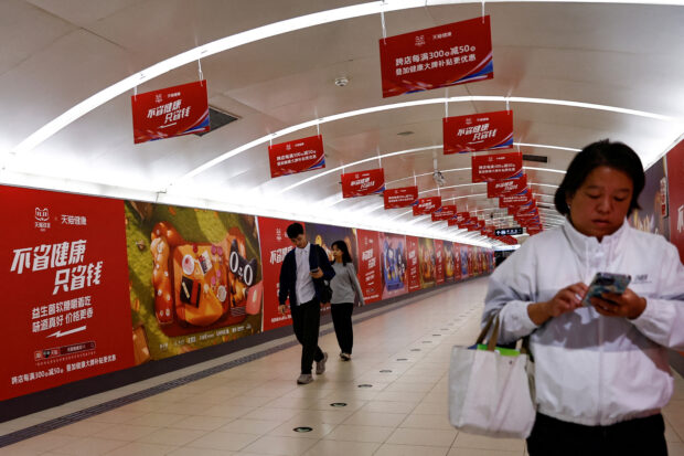 FILE PHOTO: People walk past an Alibaba's advertisement promoting Singles Day shopping festival, in Beijing