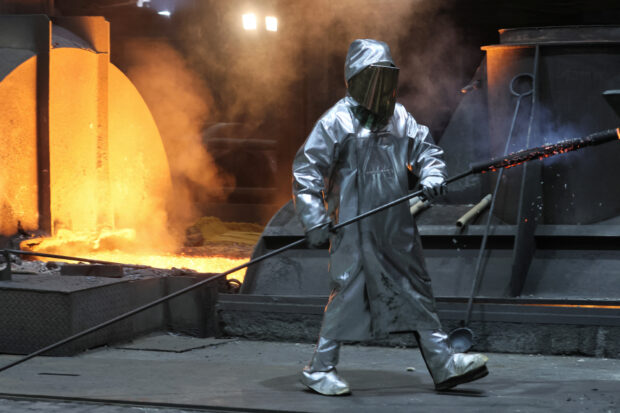 A worker walks past a blast furnace at a ThyssenKrupp steel factory in Duisburg, western Germany