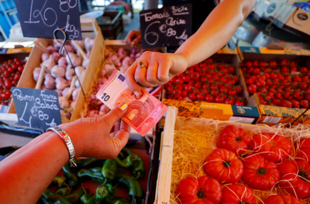 A shopper pays with a 10 euro bank note at a market in Nice