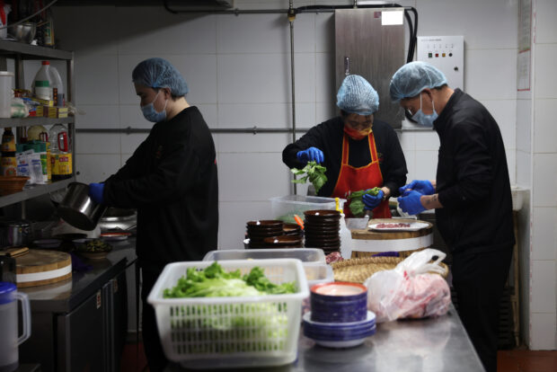 Kitchen staff prepare meat and vegetables in a hotpot restaurant in Beijing