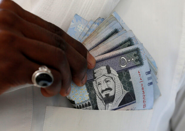 Man holds Saudi riyal banknotes