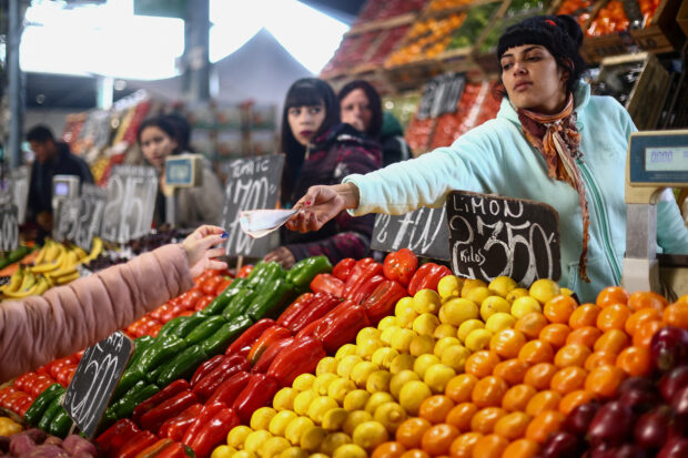 A saleswoman gives change to a customer at greengrocer's shop on the outskirts of Buenos Aires
