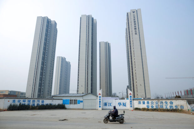 A man riding a scooter past apartment highrises in Zhengzhou, Henan province