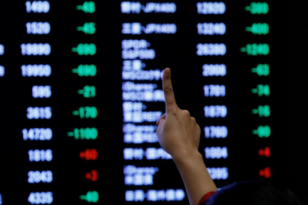 A person points to an electronic board showing stock prices at the Tokyo Stock Exchange