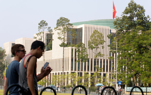 Tourists walk past Vietnam's National Assembly