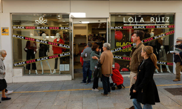 People walk past a shop in Ronda, Spain