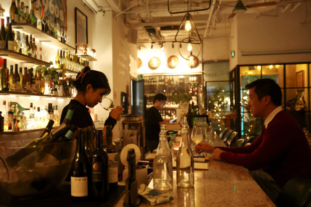 A staff member sniffs wine in a glass at the Trio Wine Bar in Beijing