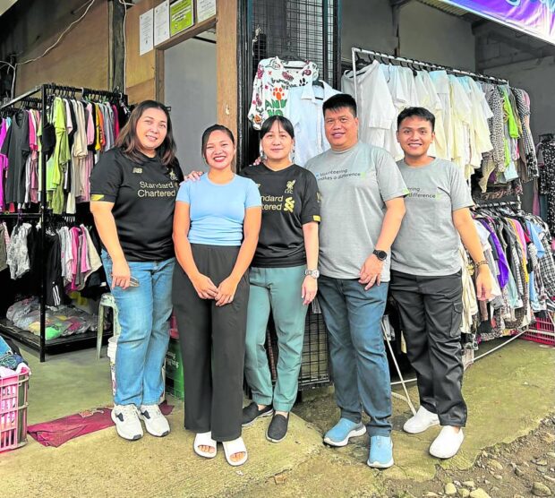 PRELOVED WARE Jenifer Chancoco (second from left), an“ukay-ukay” trader and online seller in Pili, Albay, poses with Standard Chartered Bank officers and staff. SCB Foundation partnered with microfinance firm TSPI for “Futuremakers” COVID-19 recovery lending program.