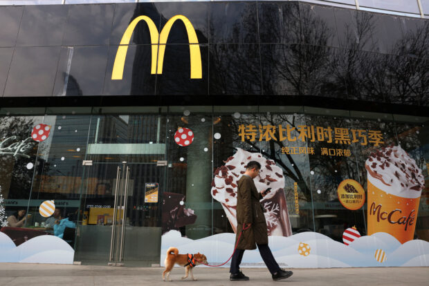A man walks a dog past a McDonald's outlet in Beijing