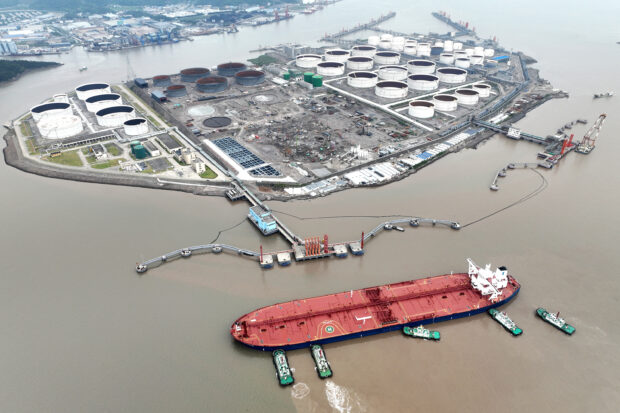 Tugboats help crude oil tanker to berth at a terminal off Waidiao island in Zhoushan