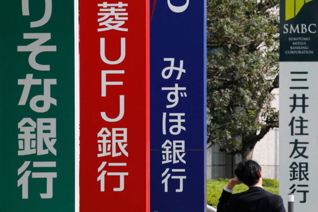 Man walks past signboards of Japanese banks