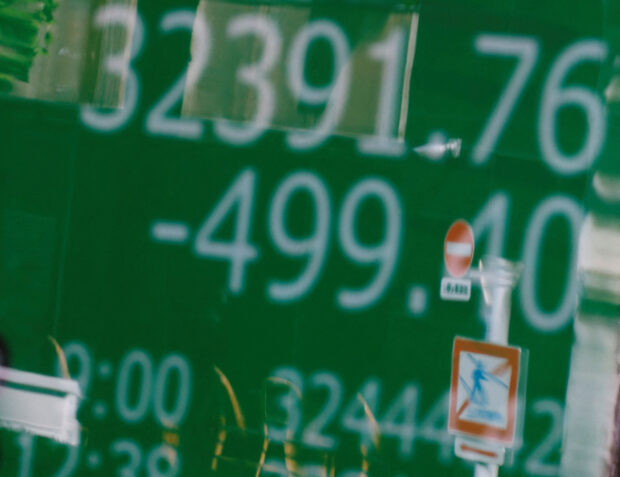 Road signs reflected on an electric board showing the Nikkei stock average in Tokyo