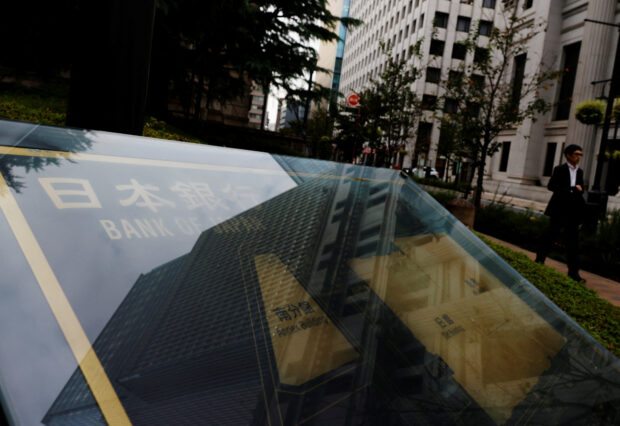 A man walks past a sign of Bank of Japan outside its headquarters in Tokyo