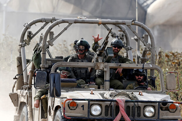 Israeli soldier gestures while riding in a military vehicle