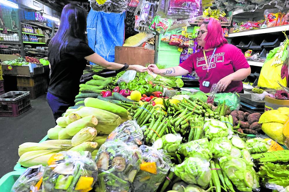 BOON TO BUYERS A customer buys fresh vegetables at a stall in Kamuning Public Market in Quiezon City. According to the Bangko Sentral ng Pilipinas, lower prices of vegetables and petroleum products along with the peso appreciation could [have contributed] to downward price pressures last month. —GRIG C. MONTEGRANDE